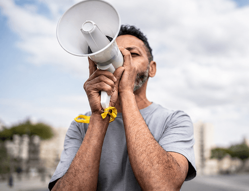A man raising a megaphone to his mouth while advocating outdoors